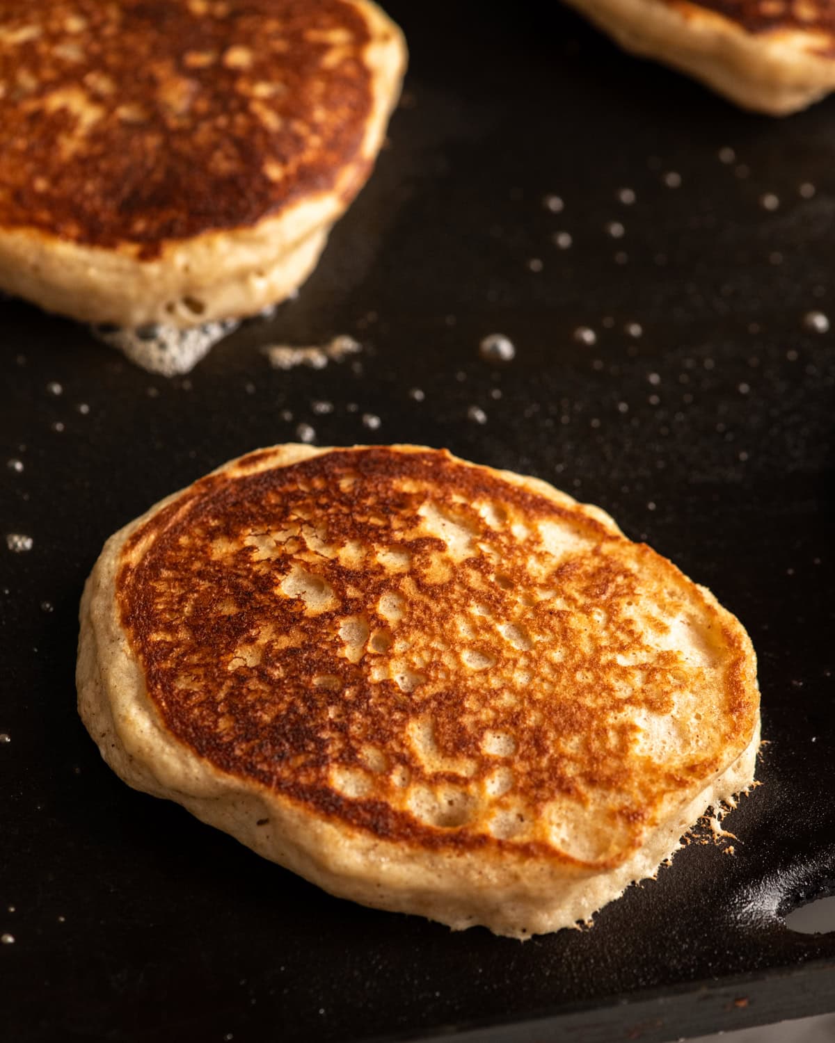 Whole Wheat Pancakes cooking on the second side on an electric griddle
