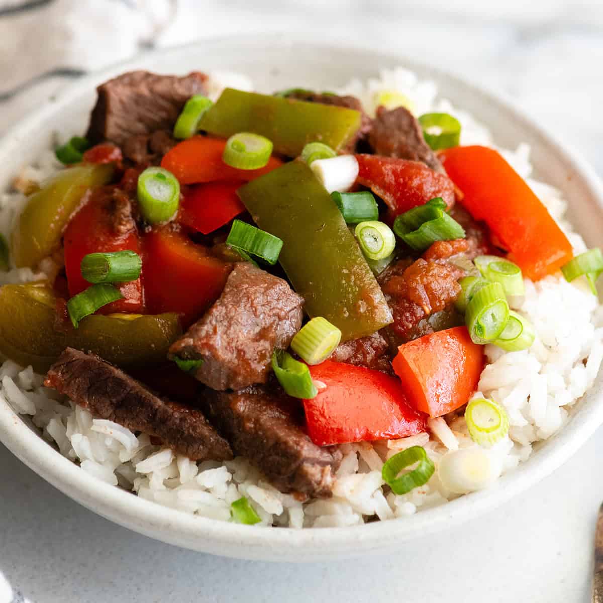 Slow Cooker Pepper Steak Recipe in a bowl over rice 