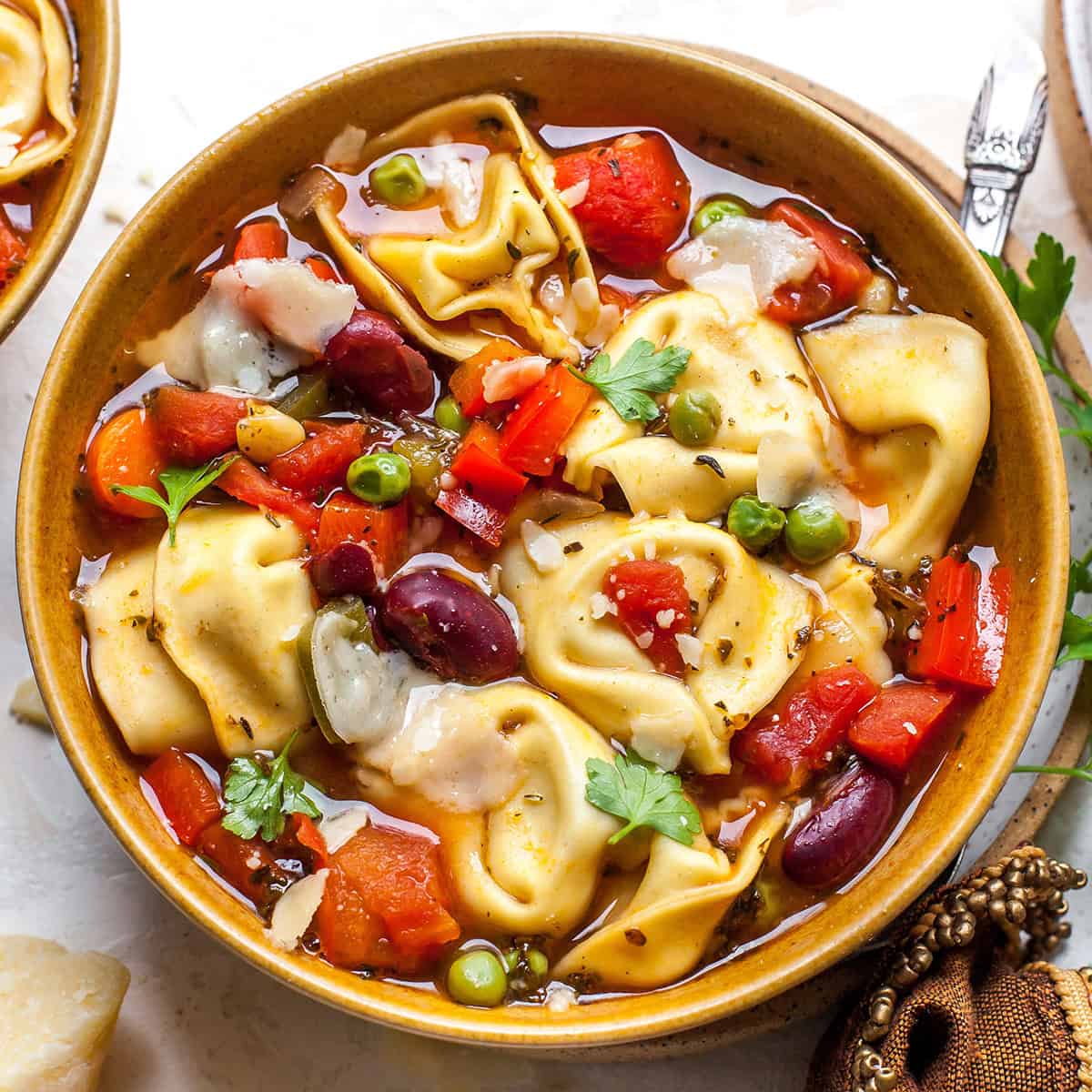 Tortellini Soup Recipe in a bowl garnisehd with parmesan cheese