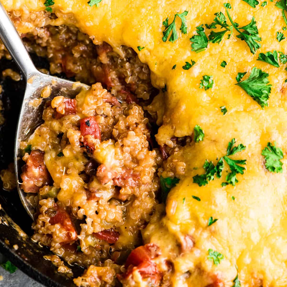 up close photo of a spoon taking a scoop of quinoa casserole out of a skillet
