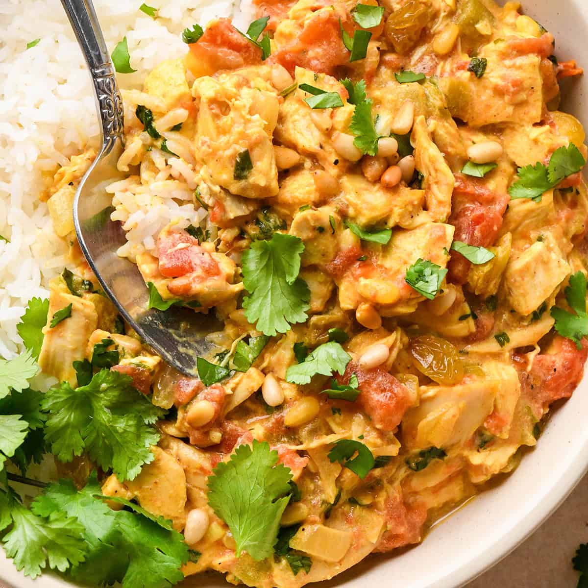 a spoon taking a scoop of Easy Chicken Curry in a bowl with rice