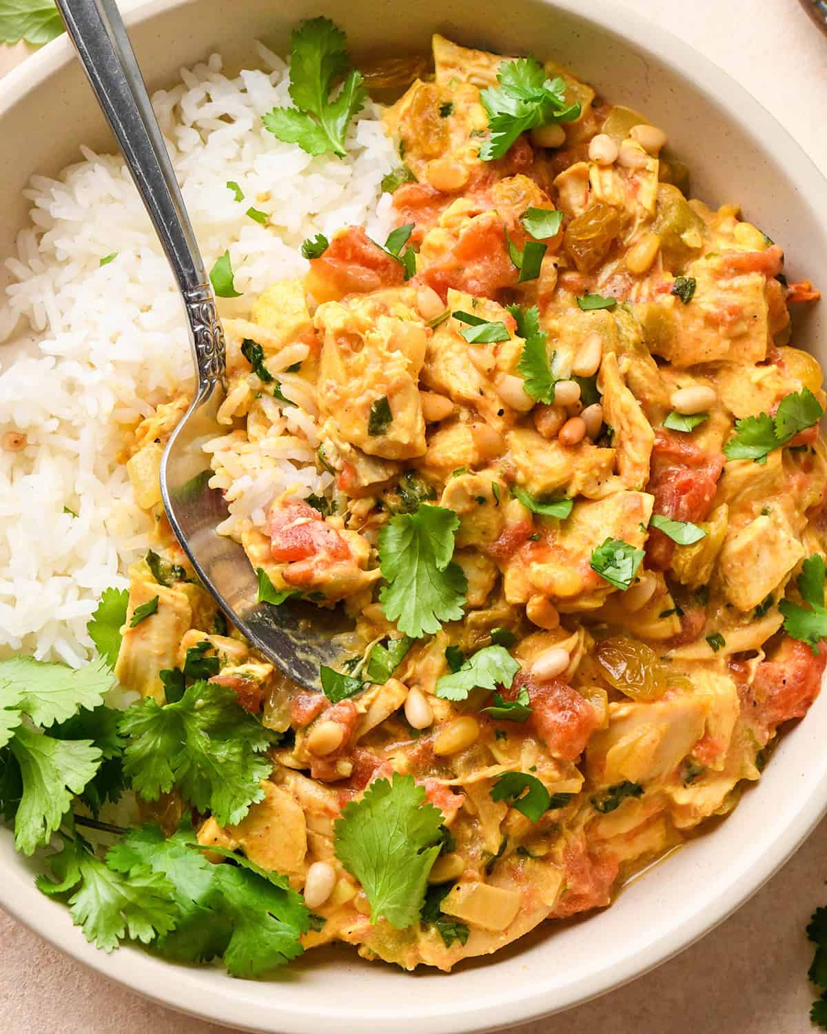 a spoon taking a scoop of Easy Chicken Curry in a bowl with rice