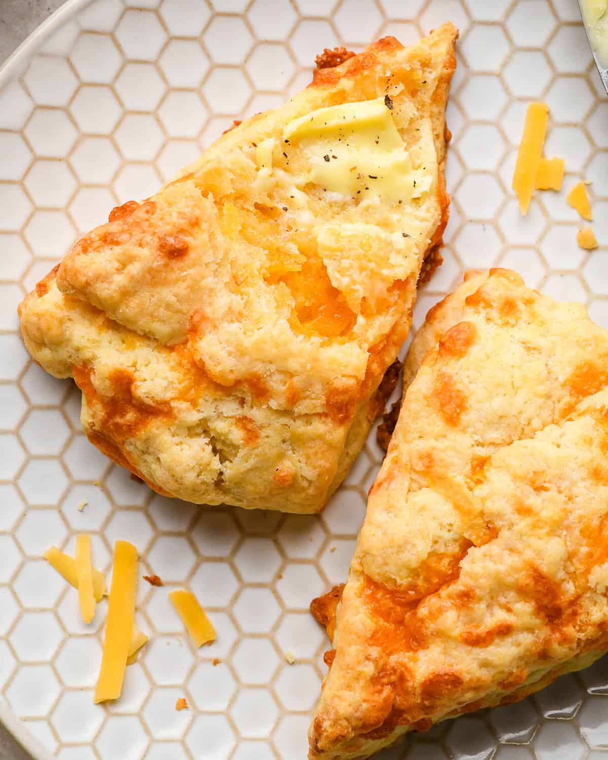 two Cheese Scones on a plate with butter spread on top of one