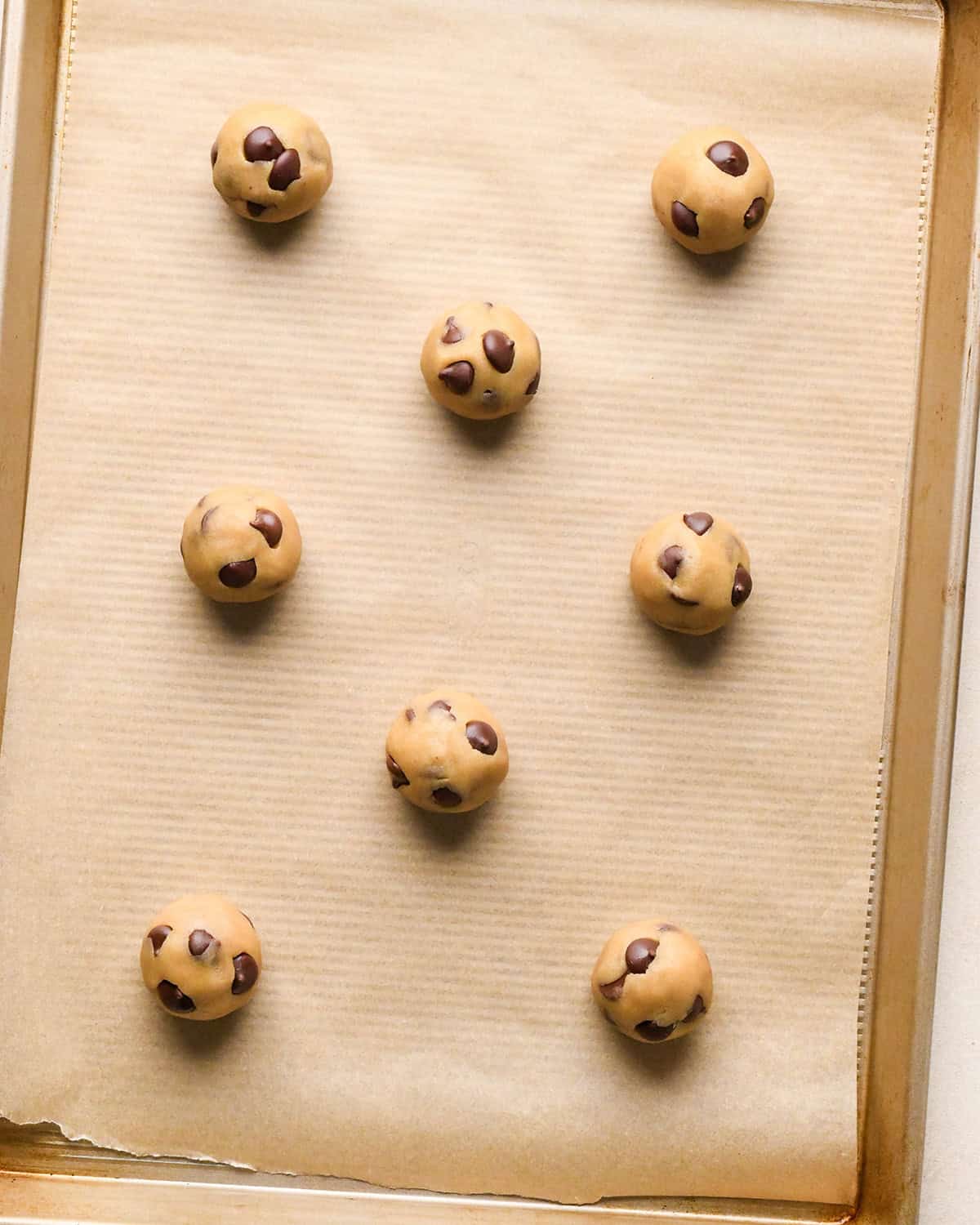 How to Make Eggless Chocolate Chip Cookies - 8 cookie dough balls on a baking sheet before baking