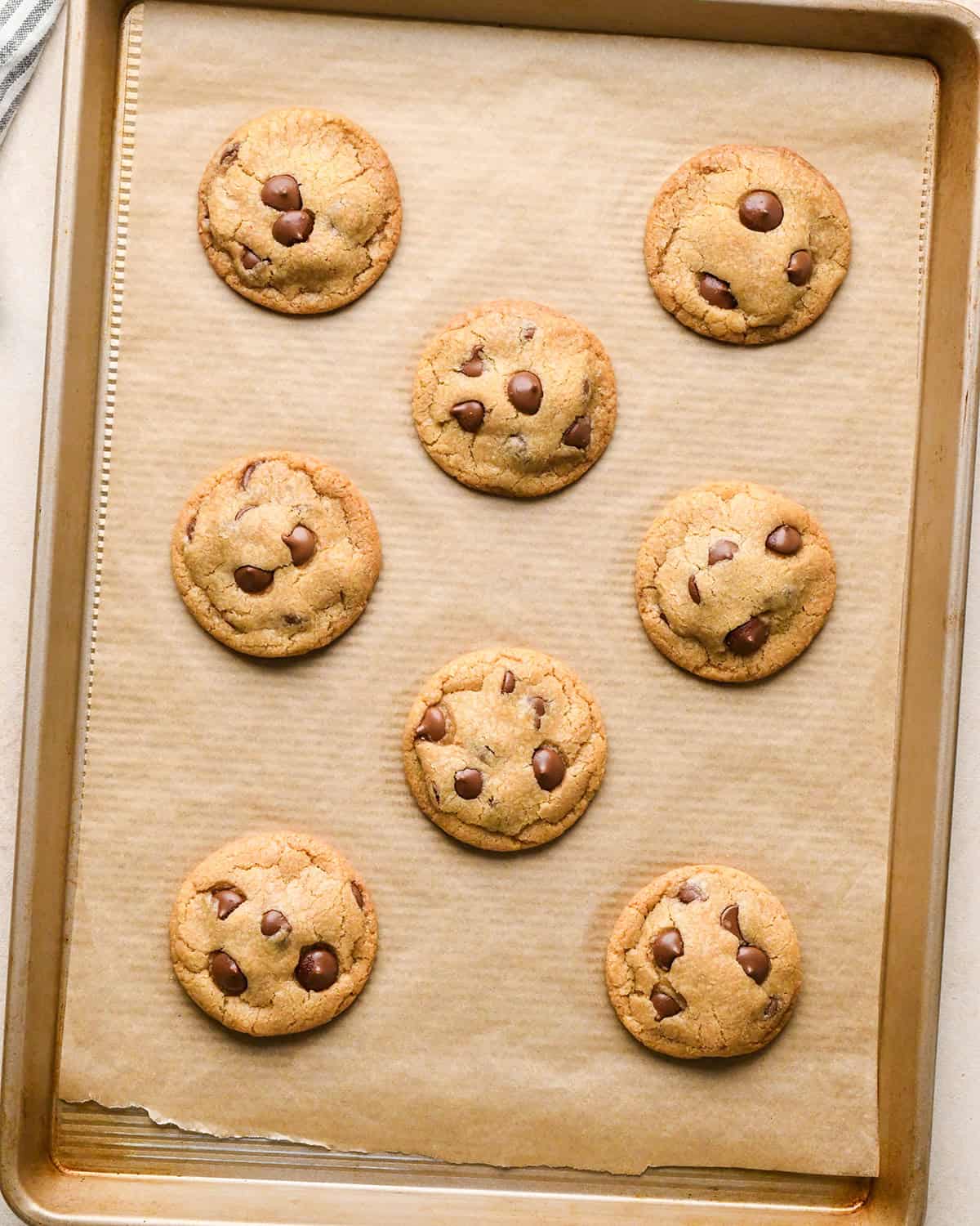 8 eggless chocolate chip cookies on a  baking sheet after baking