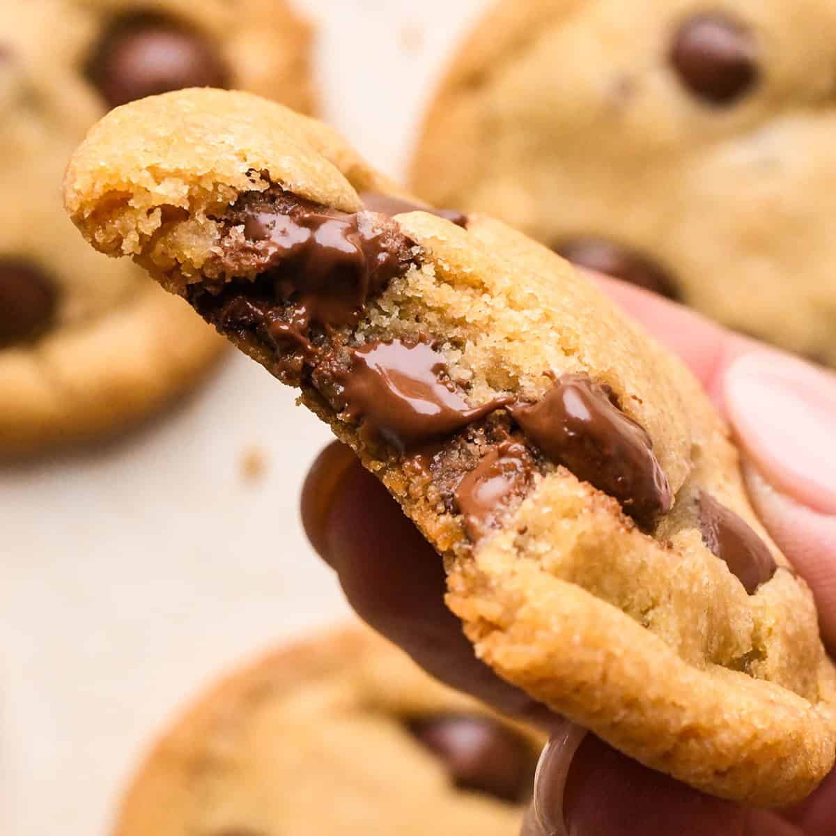 a hand holding an Eggless Chocolate Chip Cookie with a bite taken out of it