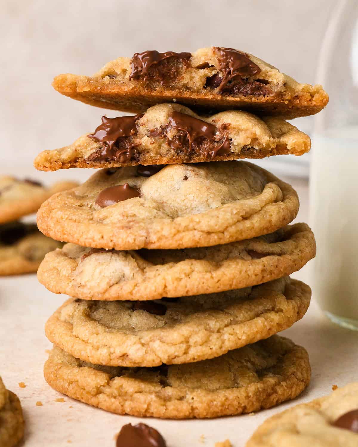 a stack of 5 Eggless Chocolate Chip Cookies, the top one is cot in half so the inside is visible. 