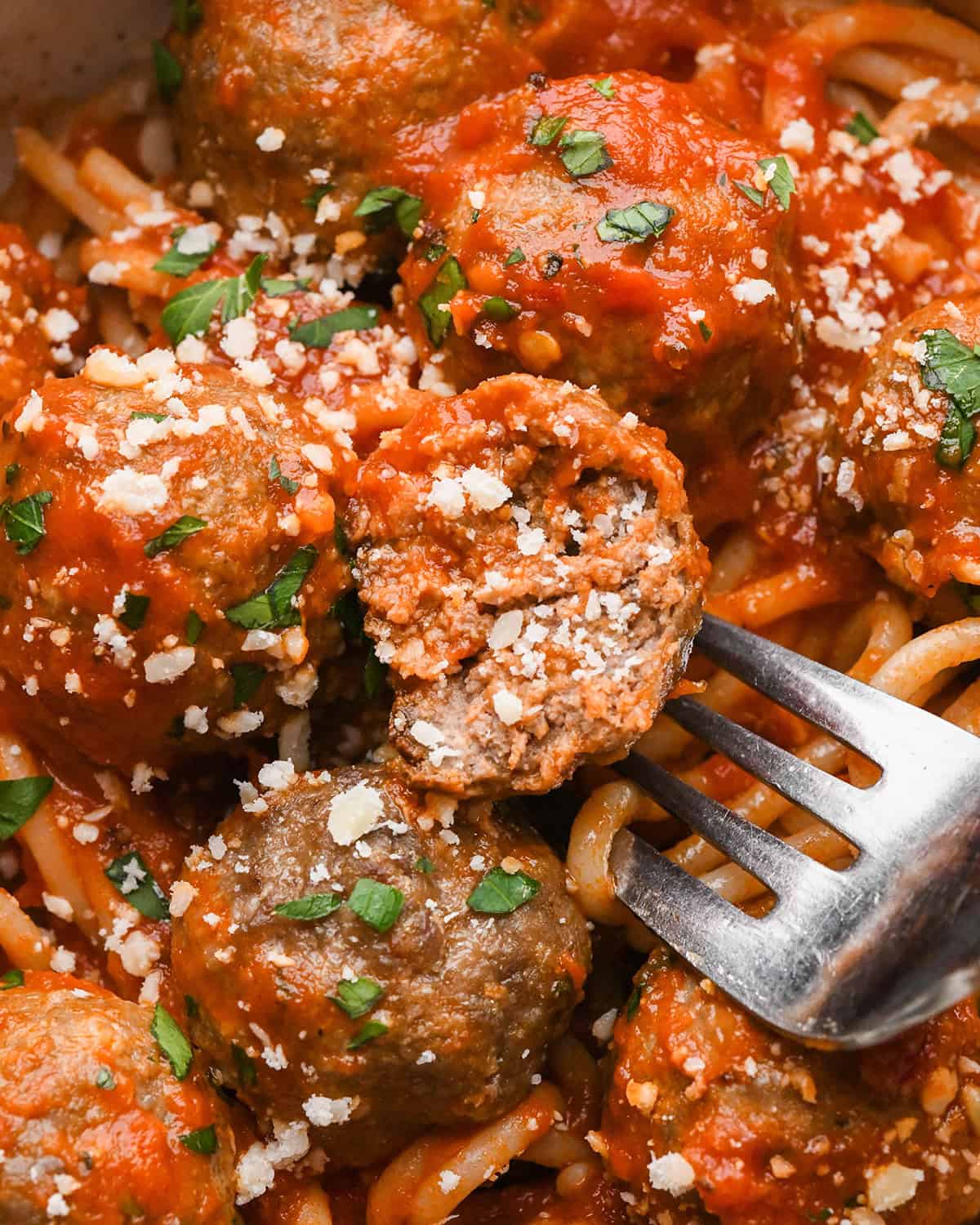 a fork with half of a Gluten Free Meatball on it in marinara sauce