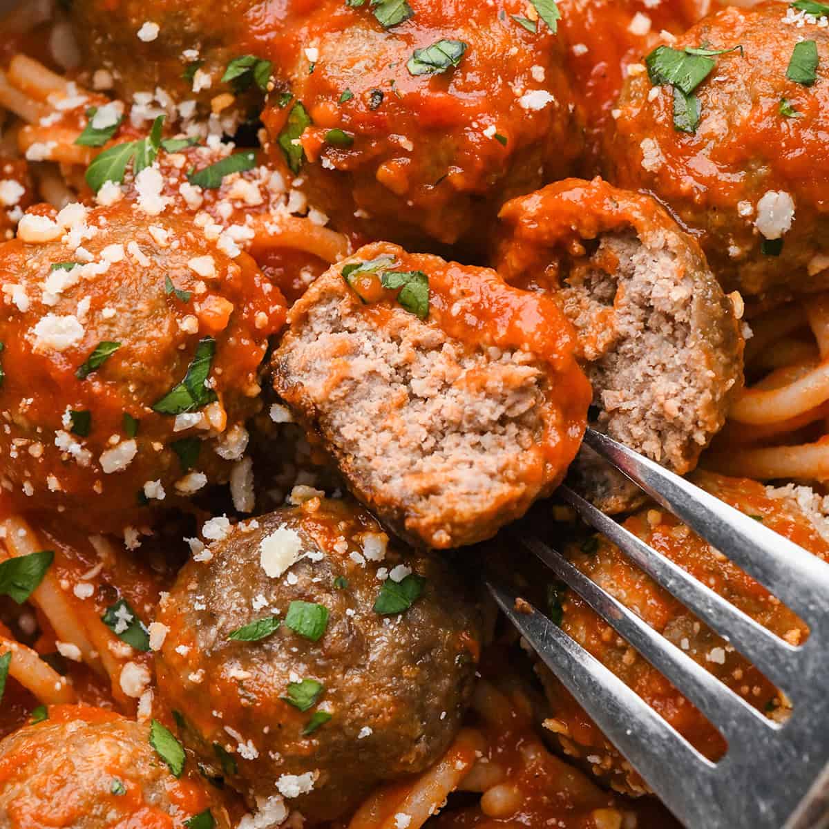 Gluten Free Meatballs in marinara sauce, one cut in half on a fork