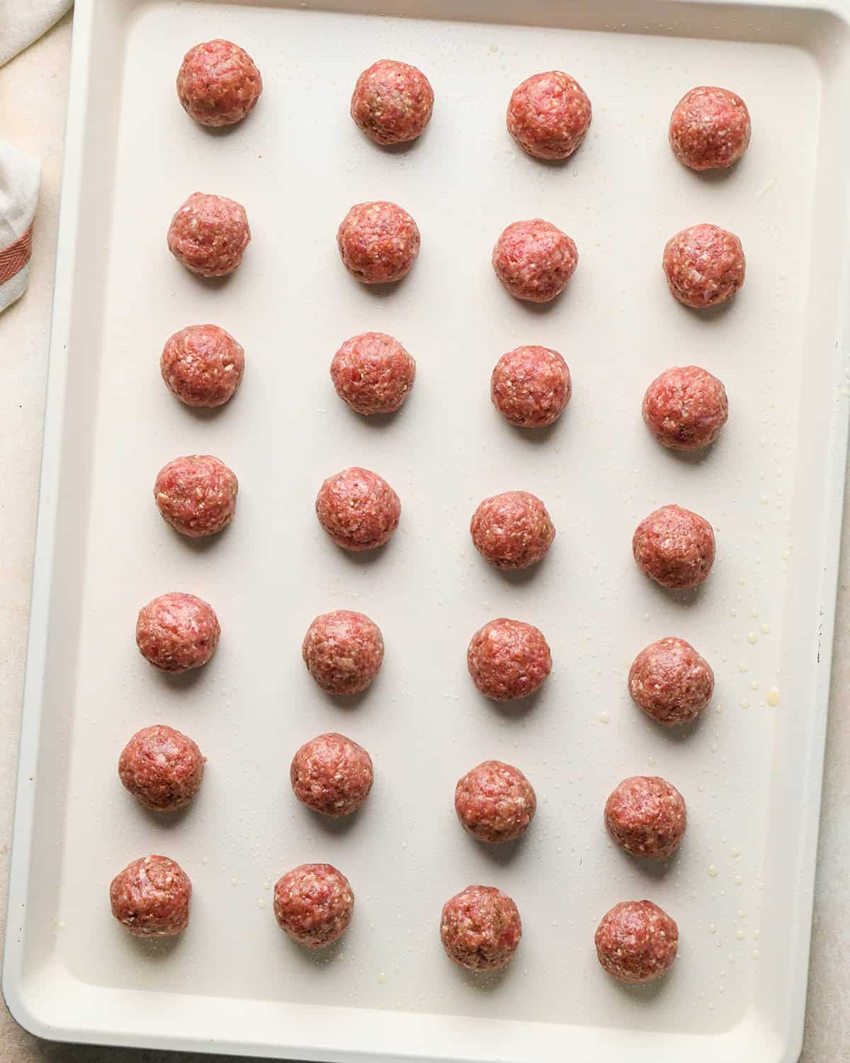 28 gluten free meatballs on a baking sheet before baking