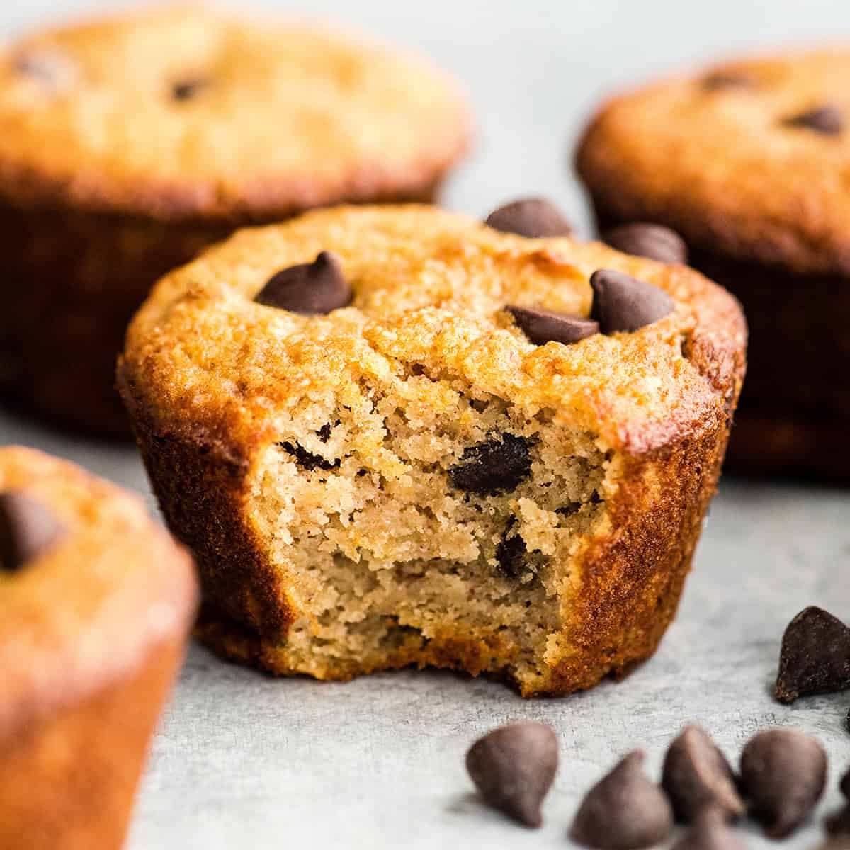 4 Gluten Free Chocolate Chip Muffins, one with a bite taken out of it