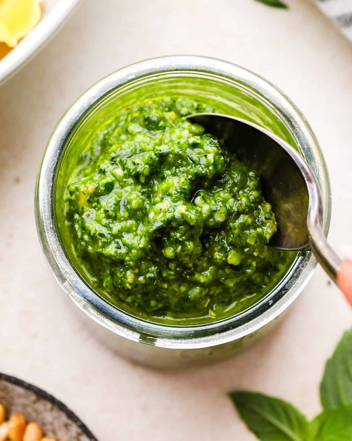 Homemade Basil Pesto Sauce in a glass jar with a spoon