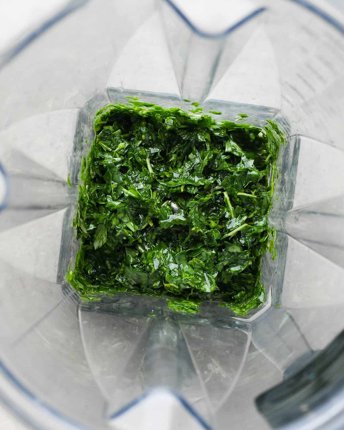 How to Make Pesto Sauce - basil leave and olive oil blended in a blending container