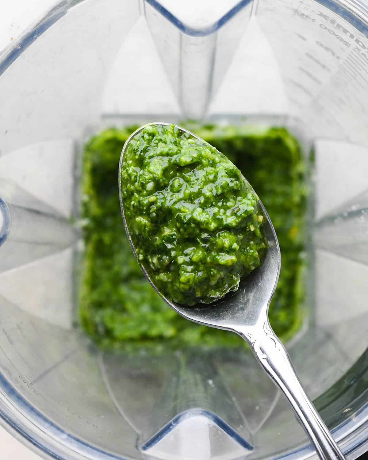 basil pesto sauce in a spoon over a blending container