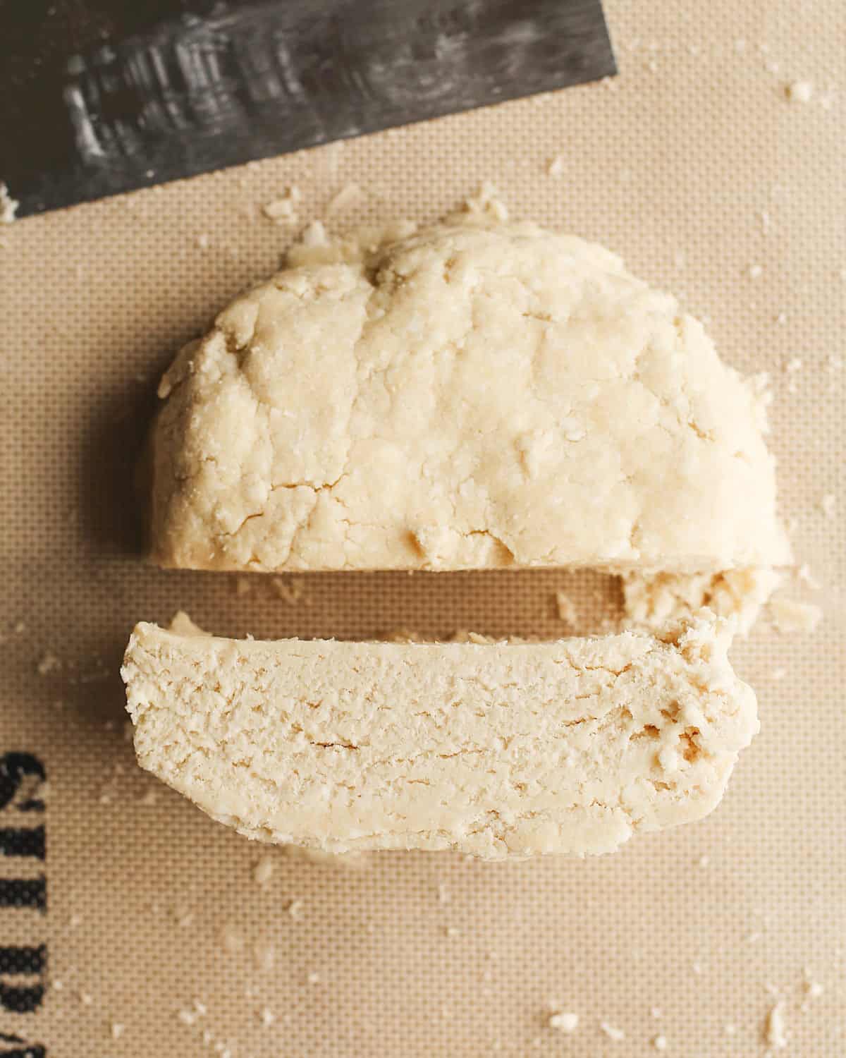 How to Make a Butter Pie Crust dough formed into a large disc cut in half 