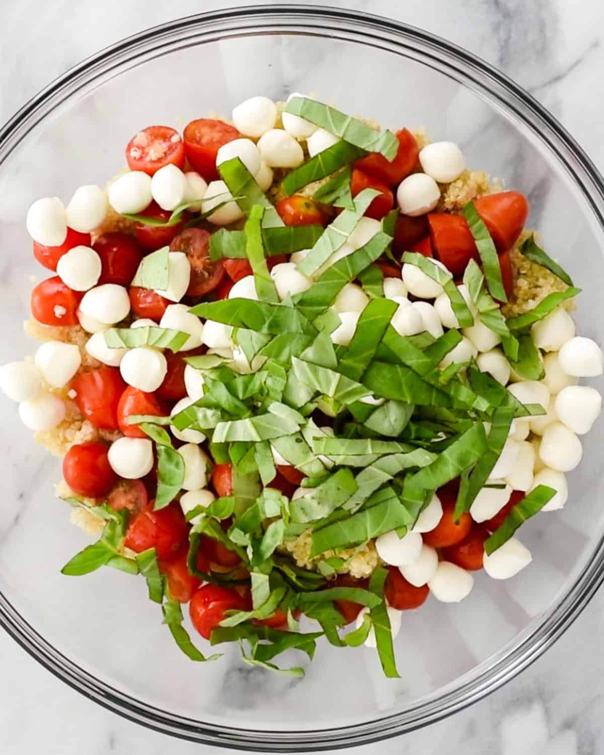 caprese quinoa salad ingredients ina  large glass bowl before mixing