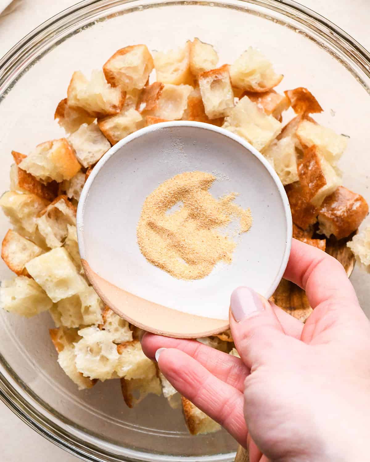 How to Make Croutons adding spice mixture to bread cubes in a bowl