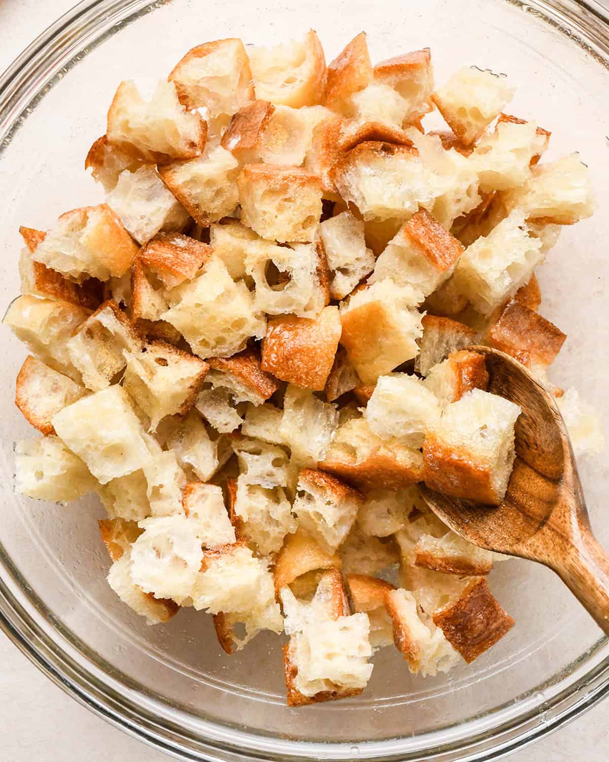 How to Make Croutons - stirring spices into bread with a wood spoon in a bowl