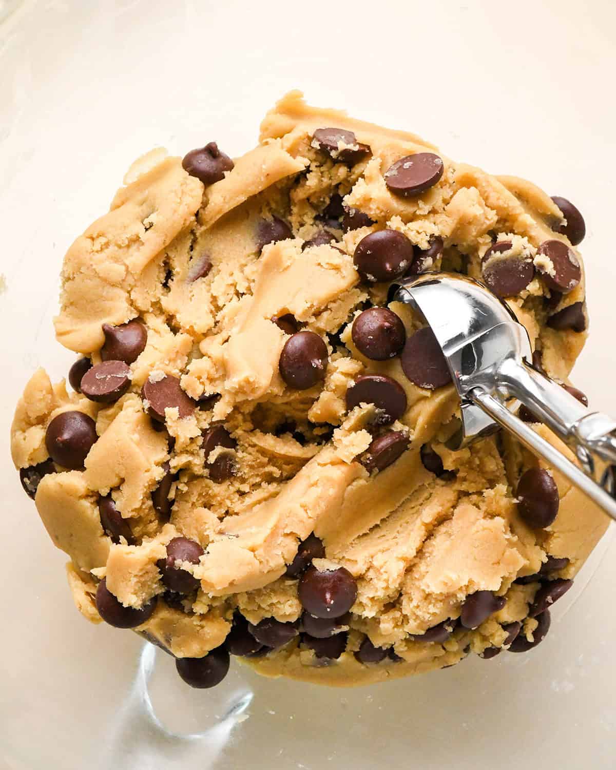 a cookie scoop scooping edible cookie dough out of a bowl