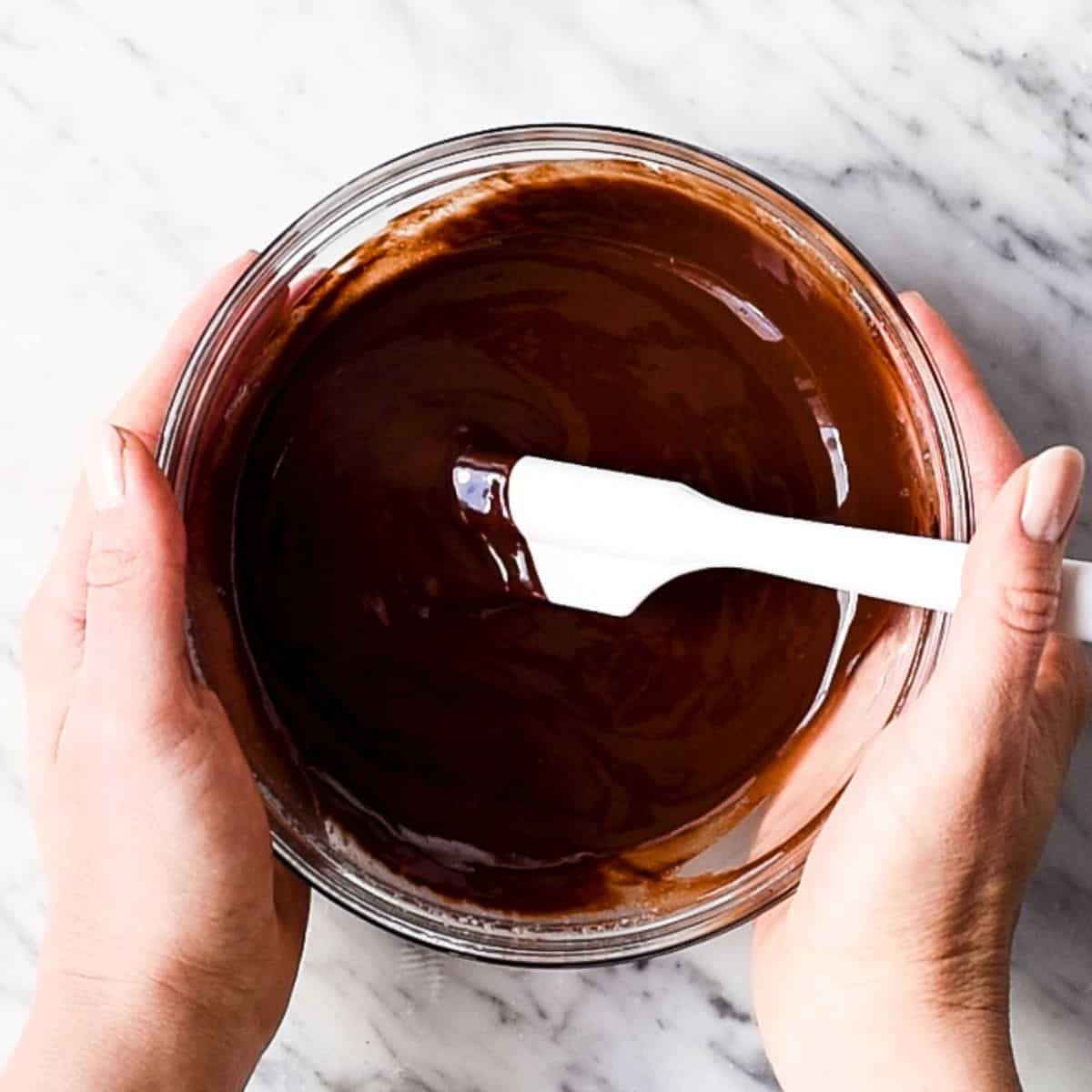 How to Make Flourless Brownies - melted chocolate & butter in a glass bowl with a white spatula