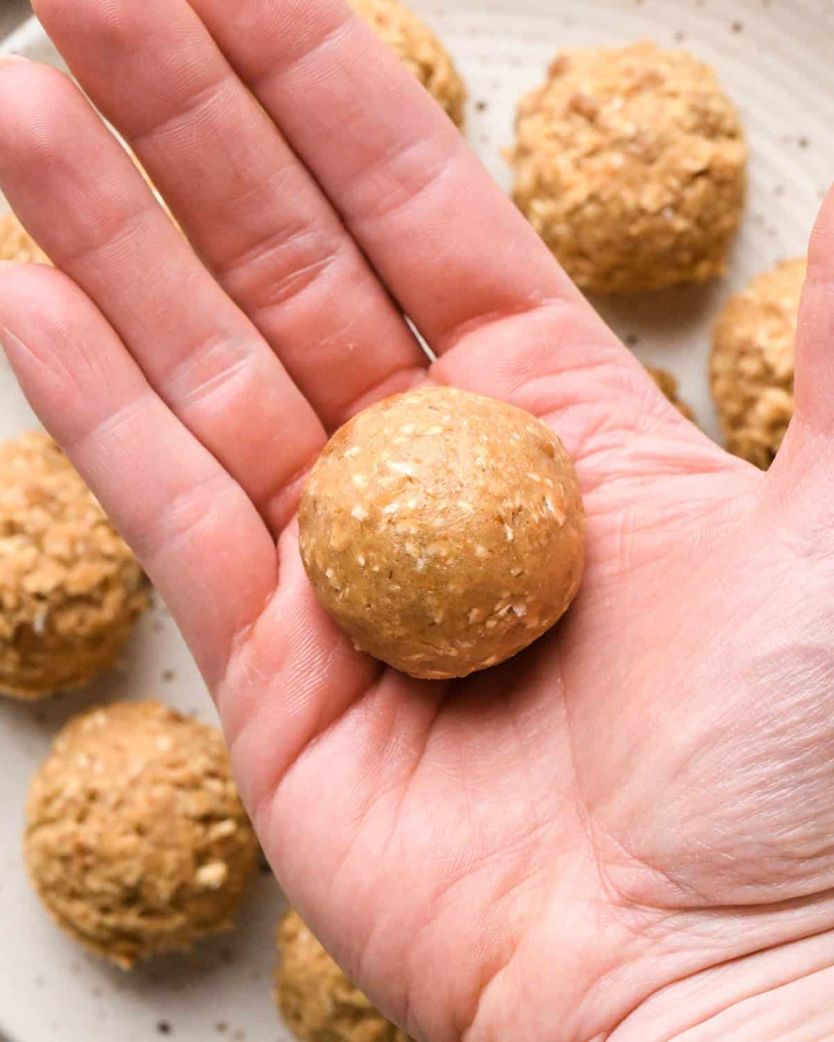 How to Make Iced Oatmeal Cookies - a hand rolling dough into a ball