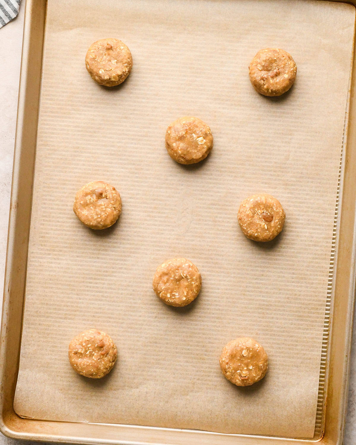 How to Make Iced Oatmeal Cookies - 8 balls of dough, slightly pressed down, on a baking sheet before baking