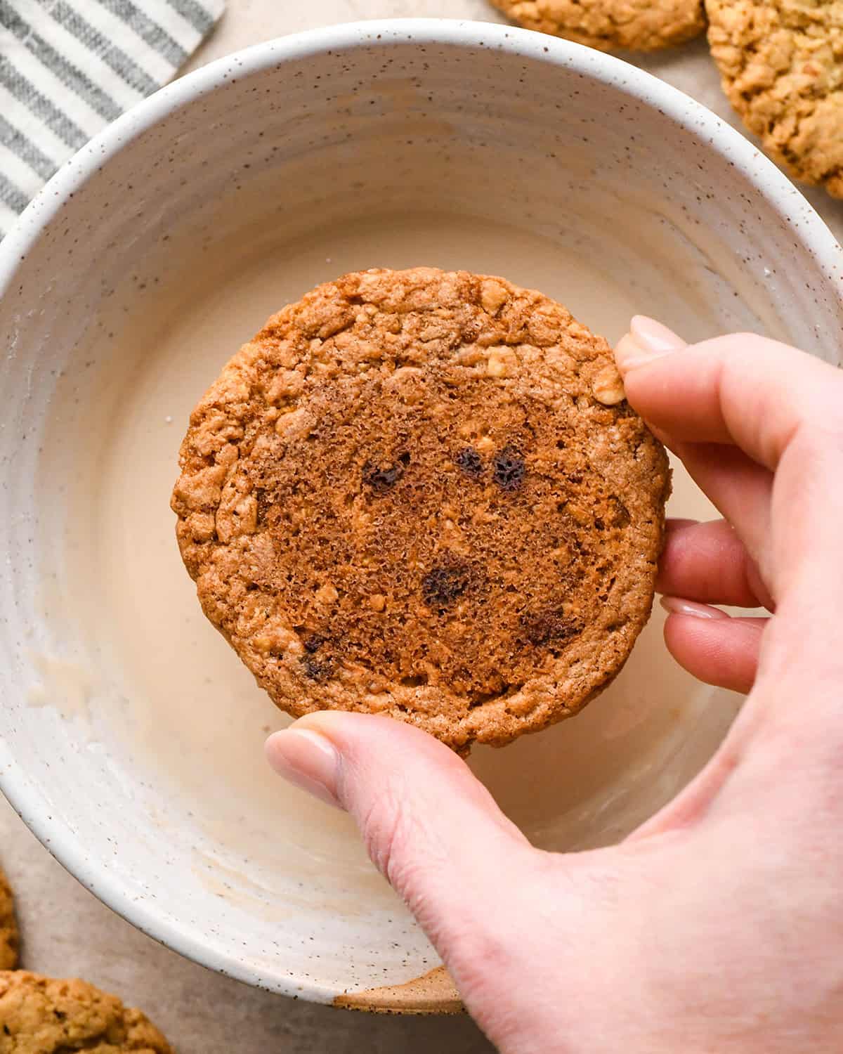 Iced Oatmeal Cookies being dipped into vanilla icing