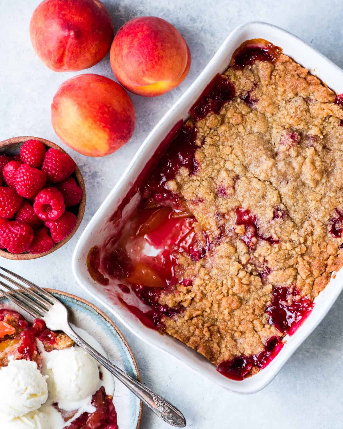 Raspberry Peach Crisp Recipe in a baking dish with a scoop removed
