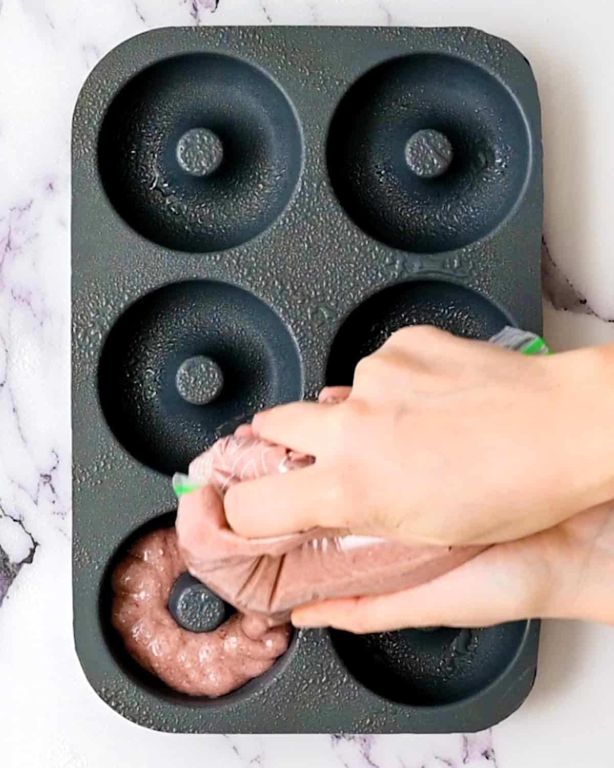 piping Baked Raspberry Donuts batter into a donut pan