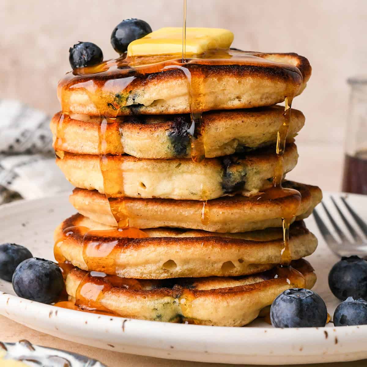 a stack of 6 Blueberry Pancakes with butter, syrup and blueberries