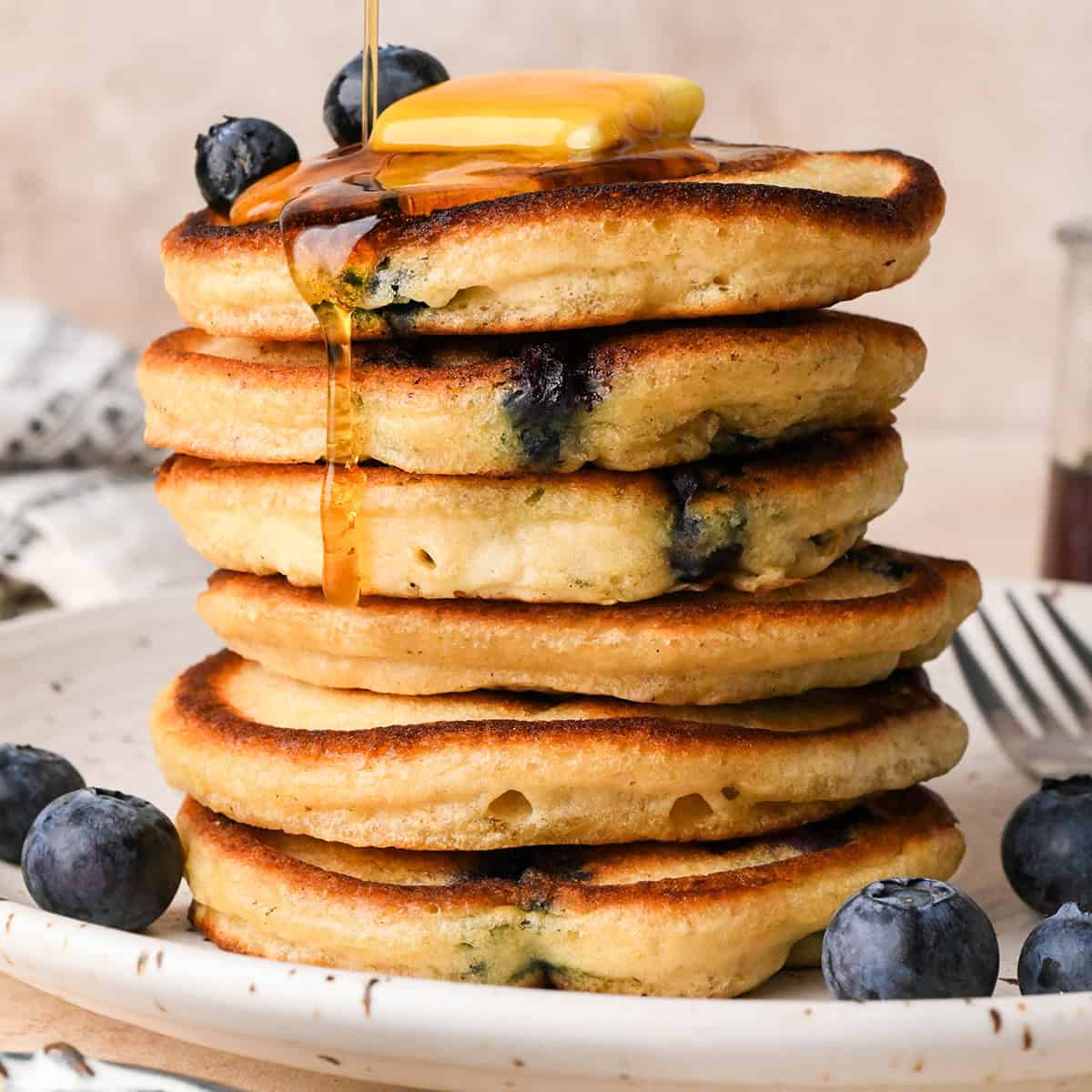 syrup being poured over a stack of 6 Blueberry Pancakes