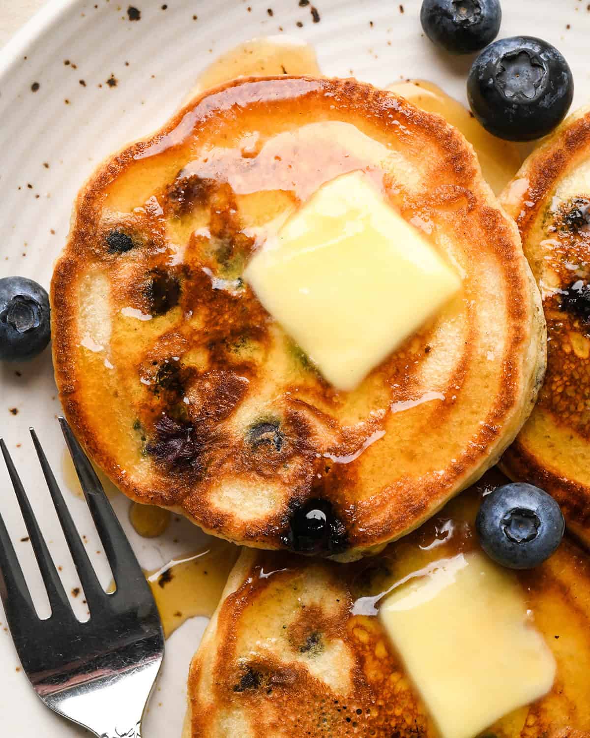 3 Blueberry Pancakes on a plate with butter and syrup