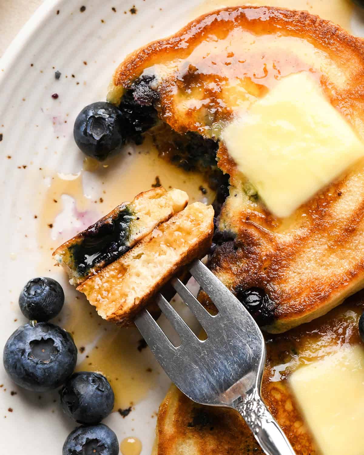Blueberry Pancakes on a plate, a fork with a bite of one in the center