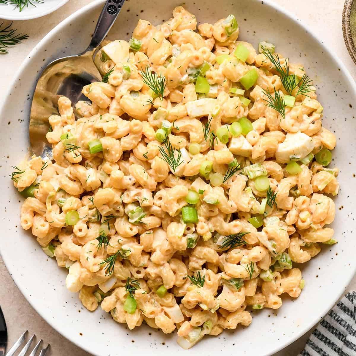 a bowl of Macaroni Salad garnished with dill and green onions