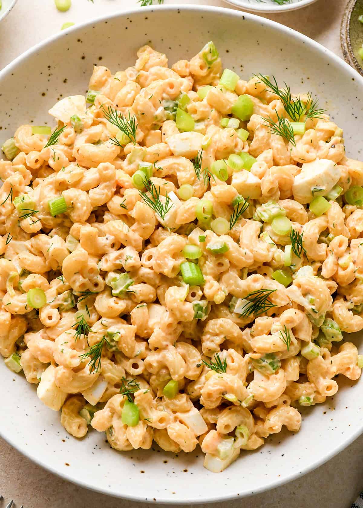 a bowl of Macaroni Salad garnished with dill and green onions
