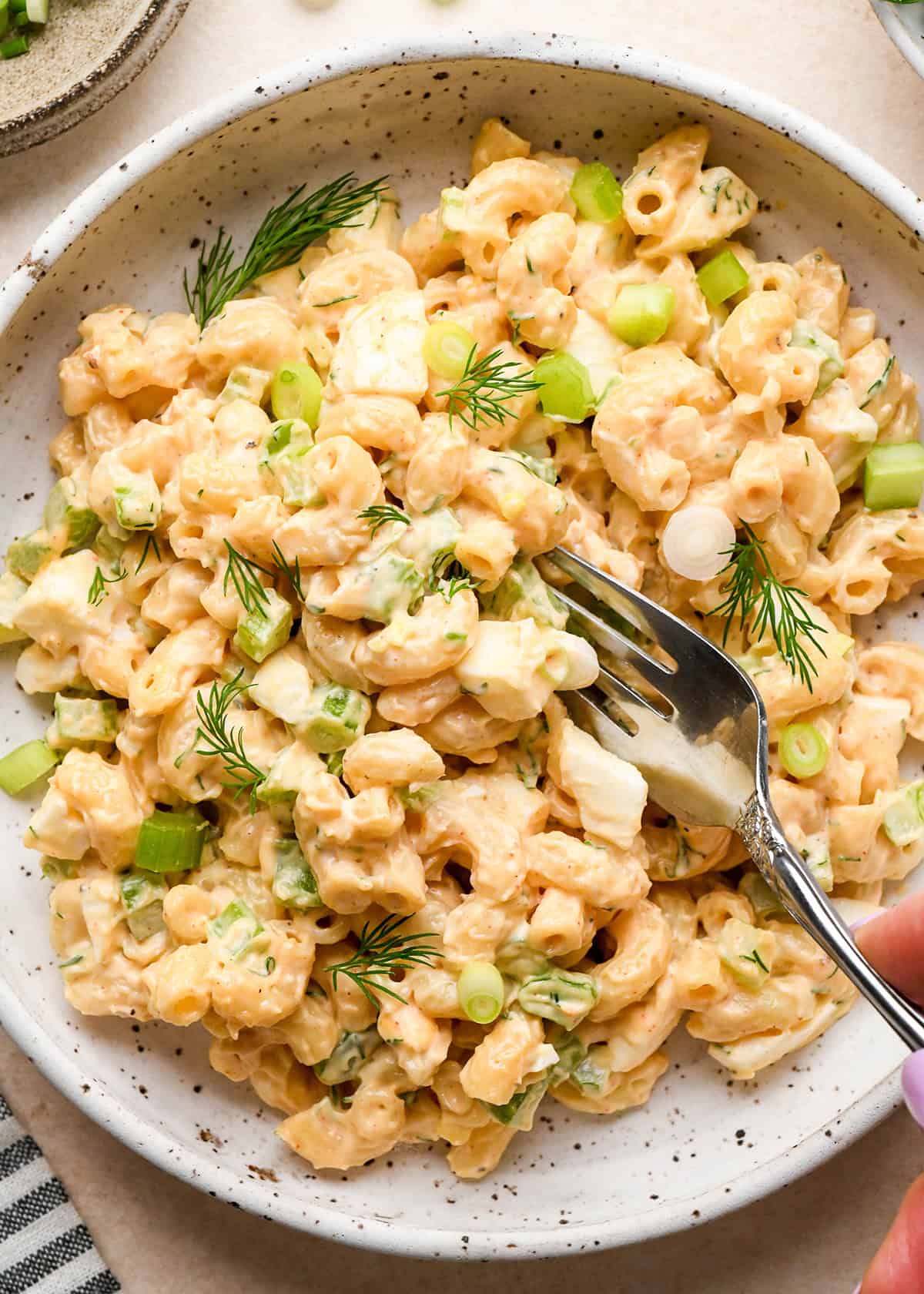 a fork taking a bite of Macaroni Salad in a bowl
