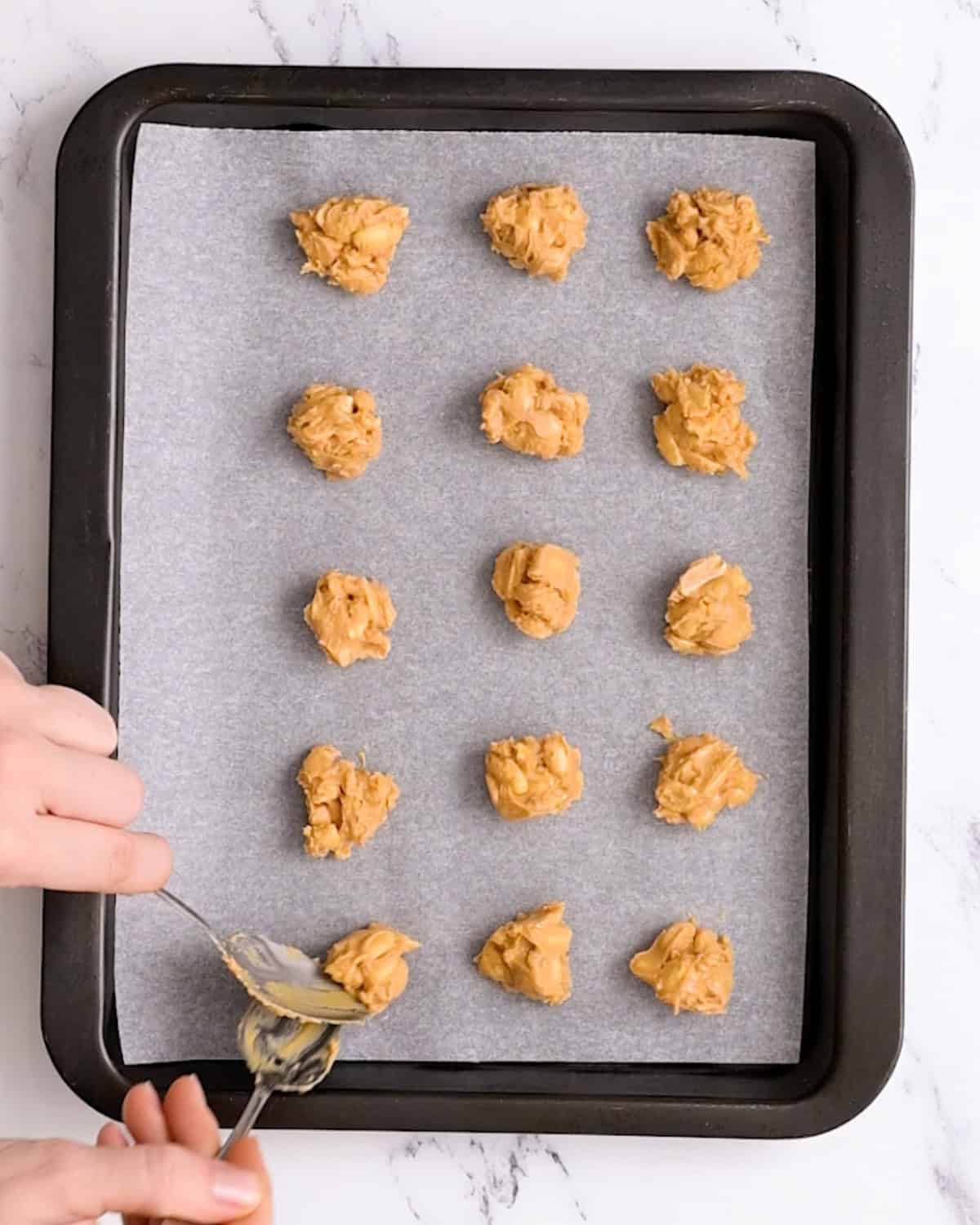 How to Make Chocolate Peanut Clusters - scooping clusters onto a baking sheet