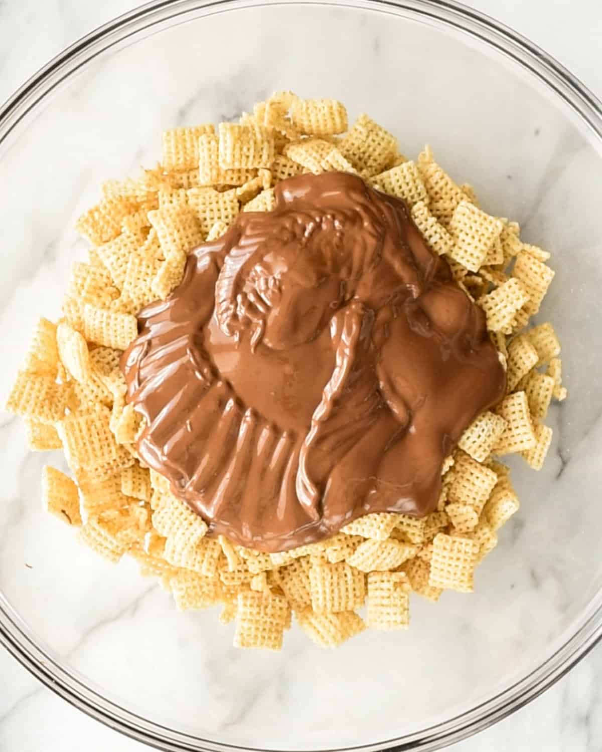 how to make dark chocolate puppy chow - melted chocolate added to chex cereal in a bowl