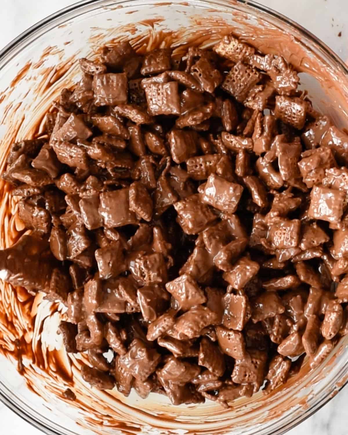 how to make dark chocolate puppy chow - cereal coated with melted chocolate peanut butter mixture in a bowl