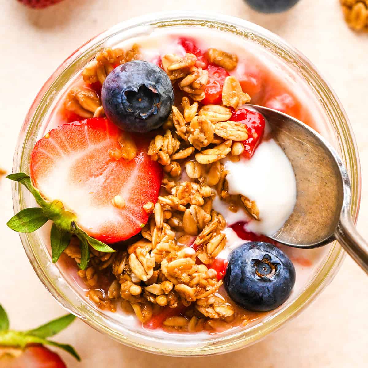 overhead photo of a spoon taking a bite of a yogurt parfait