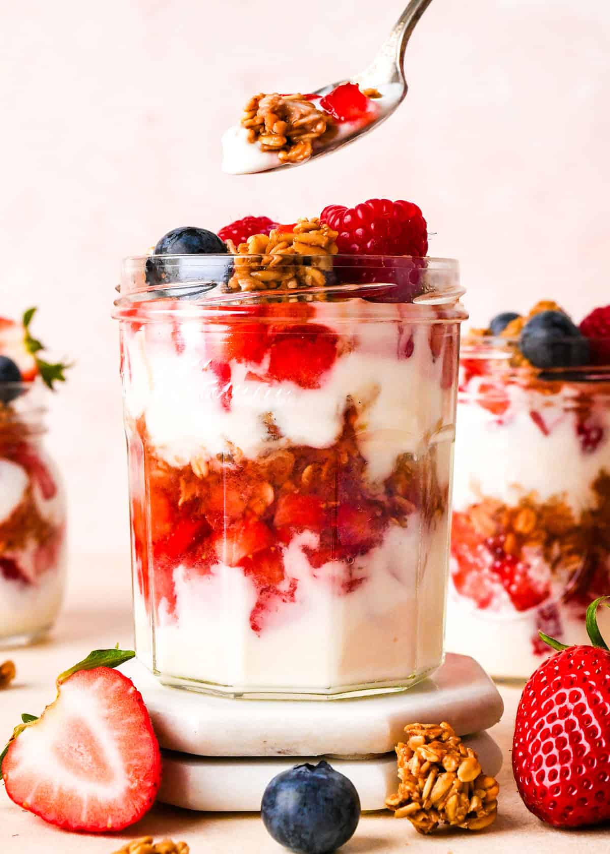 a spoon taking a bite of a yogurt parfait