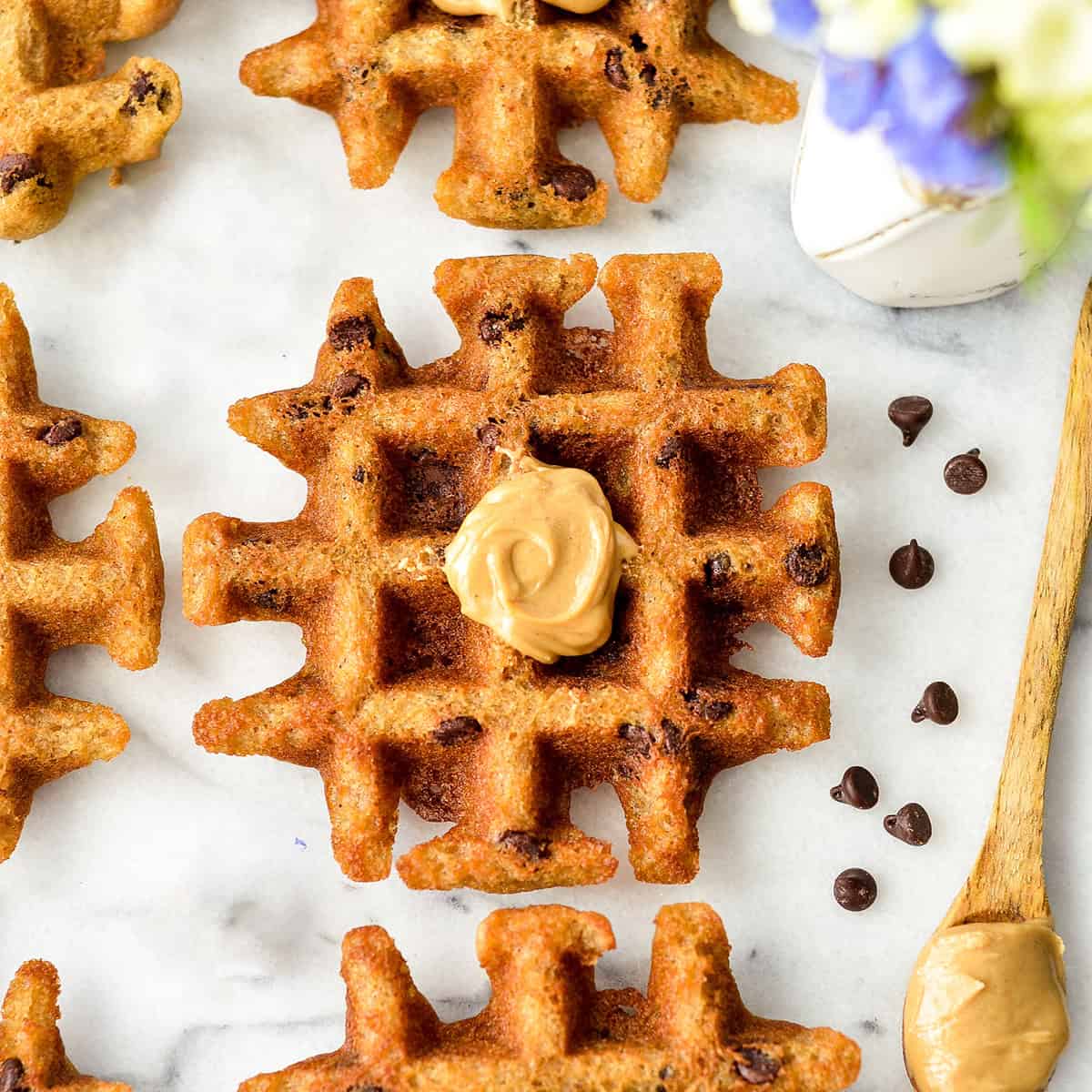 overhead photo of 4 Gluten Free Peanut Butter Waffles, one with peanut butter on top