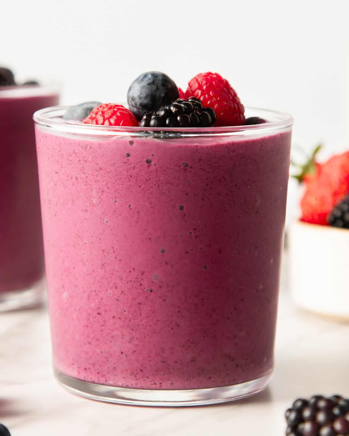greek yogurt smoothie in a glass cup topped with berries