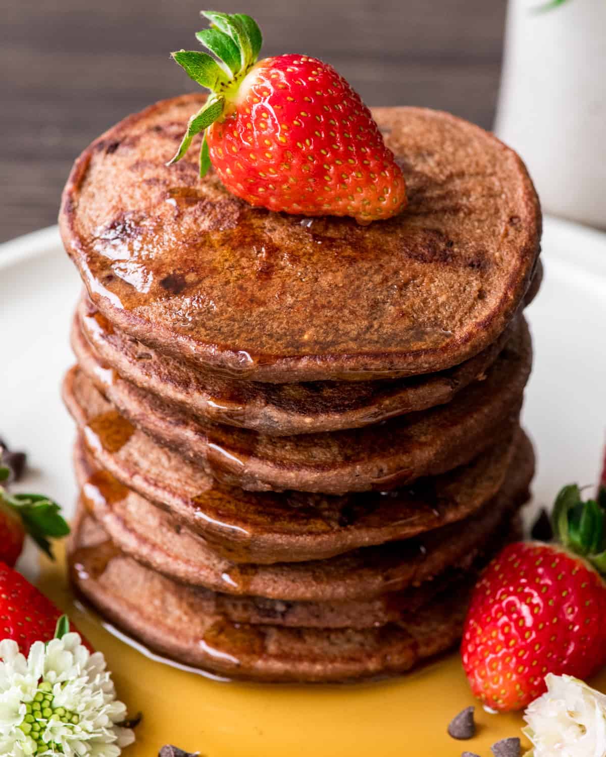 a stack of 6 Healthy Chocolate Pancakes with syrup and strawberries