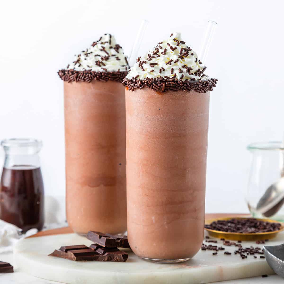 chocolate milkshake in two glasses with whipped cream and chocolate sprinkles