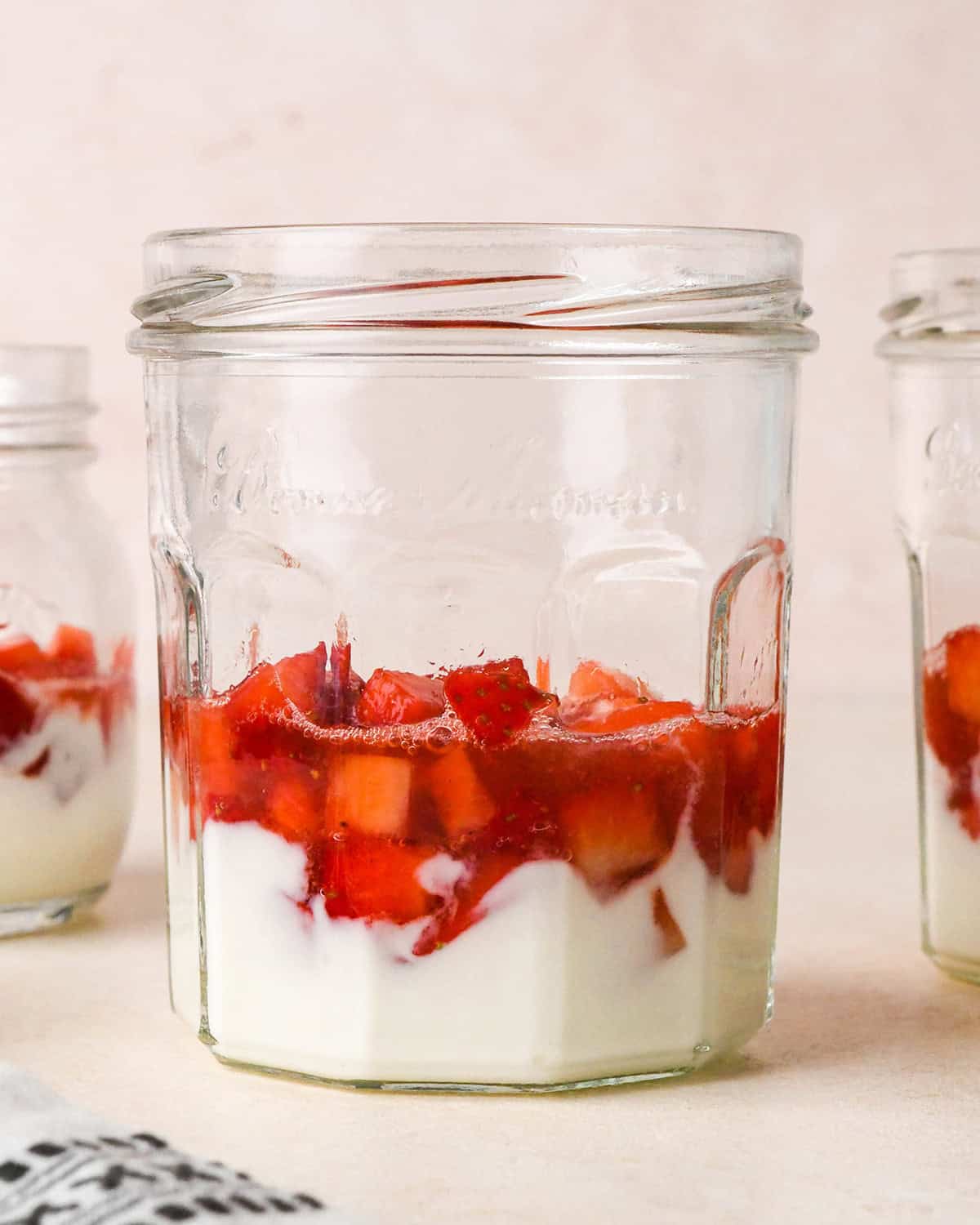How to Make a Yogurt Parfait - one layer of strawberries on top of yogurt in a jar