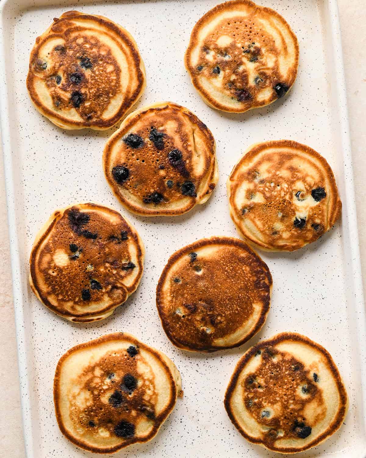 8 cooked blueberry pancakes on a baking pan