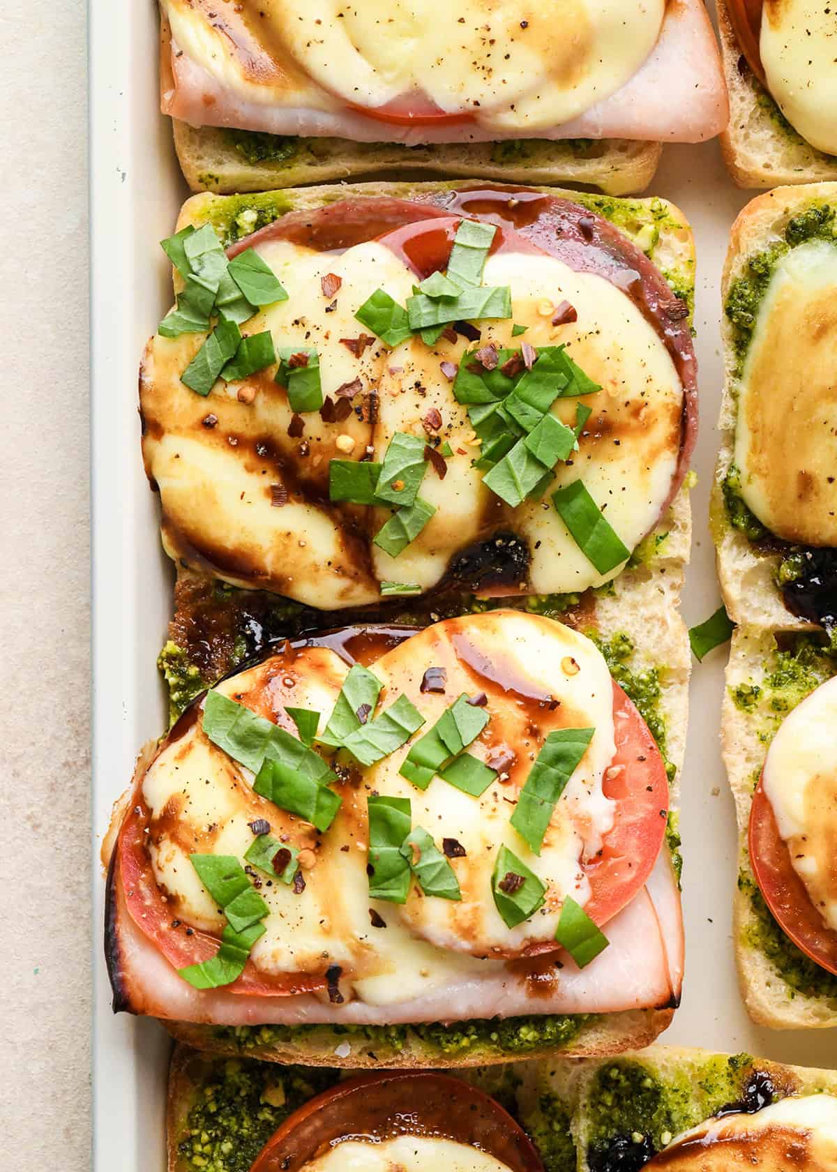 an open-faced Caprese Sandwich on a baking sheet after baking garnished with basil
