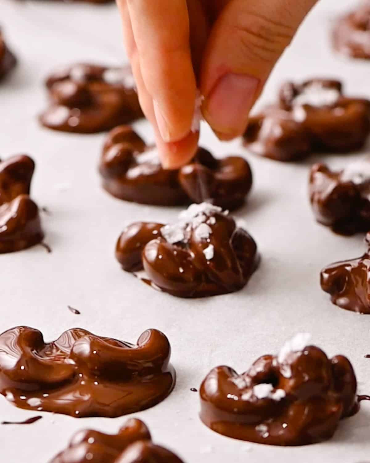 How to Make Chocolate Covered Cashews - sprinkling sea salt over cashew clusters. 