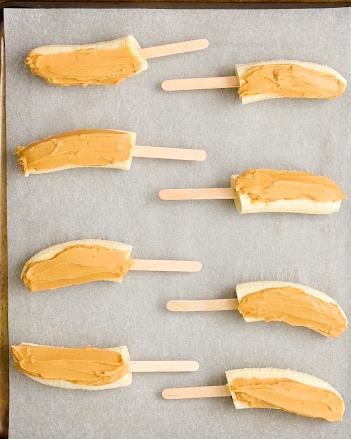8 banana halves spread with peanut butter on a wax-paper lined baking sheet